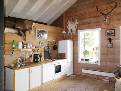 a kitchen with wooden walls and a white refrigerator at Chalet Svanöy by Interhome in Grimeli