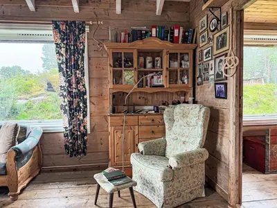 a living room with a chair and a cabinet at Chalet Svanöy by Interhome in Grimeli