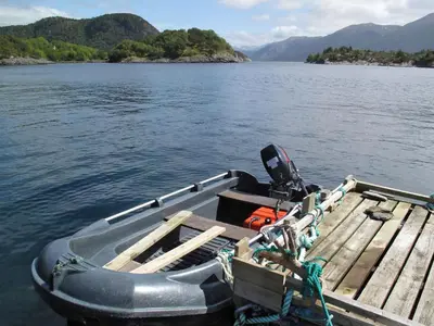 a small boat tied to a dock on a lake at Chalet Svanöy by Interhome in Grimeli