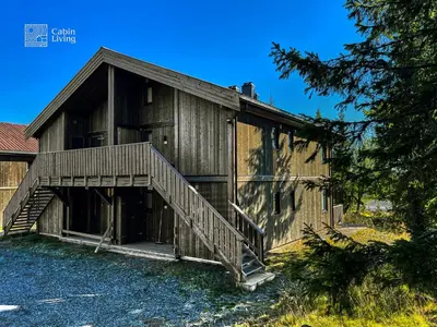 a large wooden building with a staircase in front at Cozy Apartment electric car charger & ski in out Sjusjøen in Sjusjøen