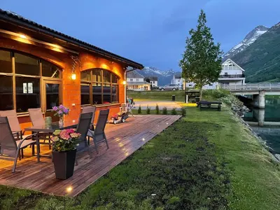 a house with a wooden deck with a table and chairs at Olden apartments 2 in Stryn