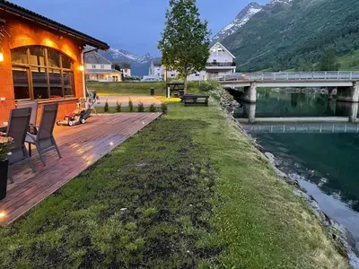 a house with a wooden deck next to a river at Olden apartments 2 in Stryn