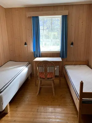 a room with two beds and a table and a chair at Voss/Bolstad: Peaceful countryside cabin/lodge in Bolstadøyri