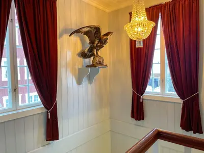 a staircase with an eagle statue in a room with windows at Finnegården Røros in Røros