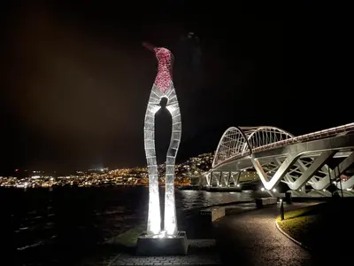 a tall sculpture of a woman on the water at night at Panorama 17 - fantastisk utsikt! in Sogndal