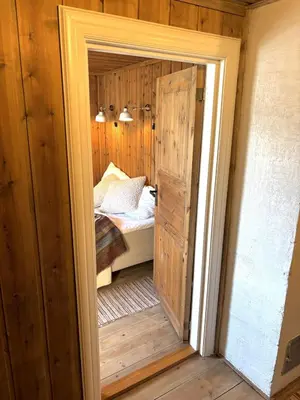 a door leading into a bedroom with a bed at Stallen - koselig lite hus på gårdstun in Skjåk