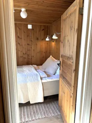 a small bedroom with a bed in a wooden room at Stallen - koselig lite hus på gårdstun in Skjåk