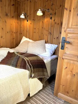 a bedroom with a bed next to a door at Stallen - koselig lite hus på gårdstun in Skjåk