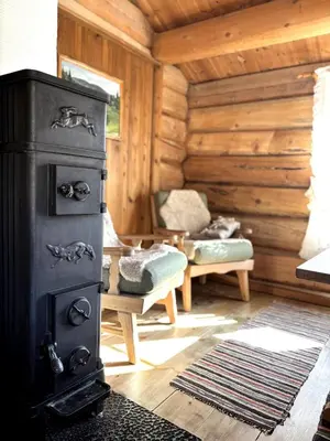 a room with a stove in a log cabin at Stallen - koselig lite hus på gårdstun in Skjåk
