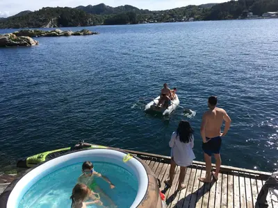 a group of people standing on a dock in the water at Bergen/Sotra: Sea cabin. Spa. Fishing. Boat in Haganes
