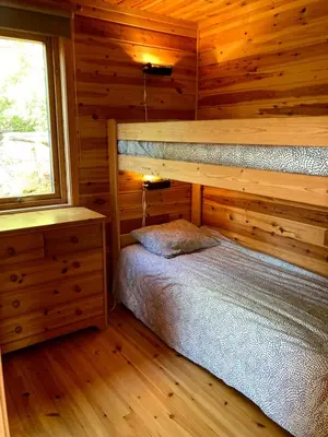 a bedroom with a bed in a wooden cabin at Bergen/Sotra: Sea cabin. Spa. Fishing. Boat in Haganes
