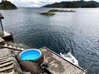 a boat sitting on a dock in the water at Bergen/Sotra:Waterfront cabin(s).Boat.Fish.Jacuzzi in Haganes