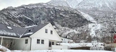 a white house in front of a snow covered mountain at Bright and cozy apartment 1.5km from city centre in Aurland