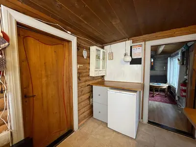 a small kitchen with a refrigerator and a door at Buhaug - cabin at Sjusjøen in Sjusjøen