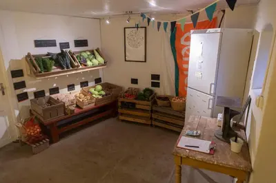 a kitchen with fruits and vegetables on shelves and a refrigerator at Fokhol Gård Gjestehus in Stange