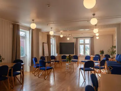 a meeting room with tables and chairs and a screen at Fokhol Gård Gjestehus in Stange