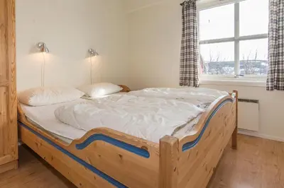 a bedroom with a wooden bed in a room with a window at Skitorget Apartments in Trysil