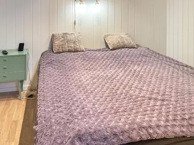 a bed with a purple comforter in a bedroom at 4 person holiday home in LINDÅS-By Traum in Lindås