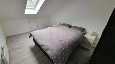 a bedroom with a bed with a purple comforter at Lovely 2-bedroom loft with panoramic view. in Kristiansund