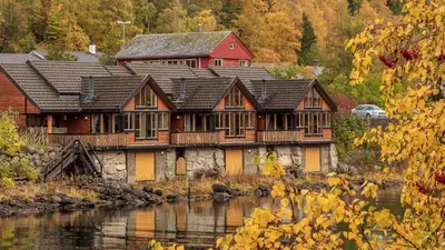 a large wooden house next to a river at Simadalsvegen 3 Hytte 2 in Eidfjord
