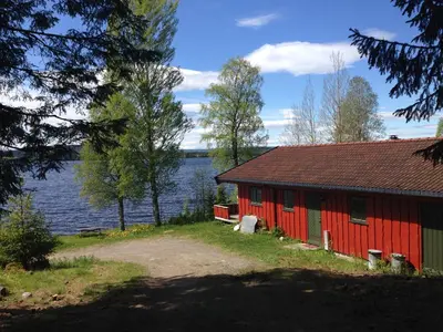 a red building next to a body of water at Festly in Ringsaker