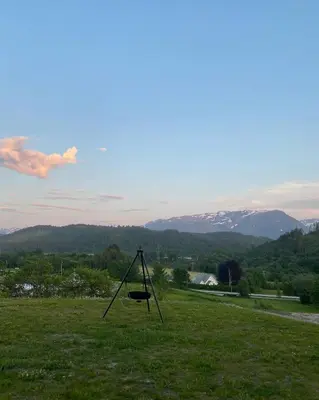a swing in a field with mountains in the background at Sjøholt Sommerhotell in Ørskog