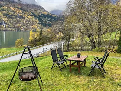 a table and chairs in the grass near a lake at 7 person holiday home in STRYN-By Traum in Stryn
