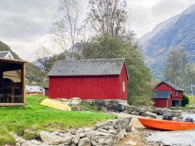 a red barn and two boats on a river at 6 person holiday home in olden-By Traum in Olden