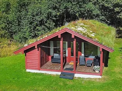 a red cabin with a grassy roof with chairs and tables at 6 person holiday home in olden-By Traum in Olden