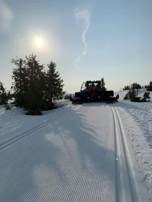 a snow truck driving down a snow covered road at Modern ski-in out apartment at Sjusjøen in Sjusjøen