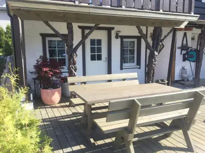 a wooden bench on a deck with a gazebo at Fjordgaestehaus in Innfjorden
