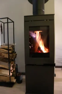 a stove with a fire in a room with books at Beautiful penthouse with panoramic view at Sjusjøen in Ringsaker