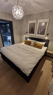 a bedroom with a large bed with a chandelier at Beautiful penthouse with panoramic view at Sjusjøen in Ringsaker