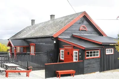 a black house with a red door and a bench at Snøhetta Camping in Hjerkinn