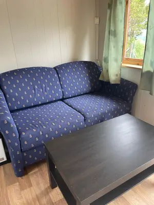 a blue couch in a living room with a coffee table at Snøhetta Camping in Hjerkinn