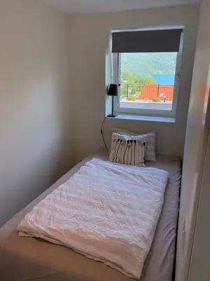 a small bedroom with a bed with a window at Havn i Etne with fjordview in Etnesjøen