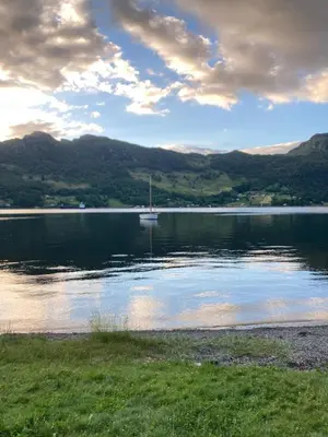 a lake with a sail boat in the water at Havn i Etne with fjordview in Etnesjøen