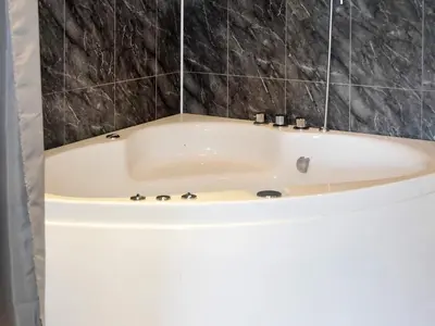a white bath tub in a bathroom with black tiles at 6 person holiday home in SANDANE-By Traum in Sandane