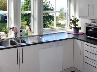 a kitchen with white cabinets and a sink and two windows at 6 person holiday home in SANDANE-By Traum in Sandane