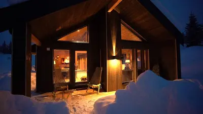 a cabin in the snow at night at Unique cabin with fantastic lake view, sauna, ski & EV outlet in Svingvoll