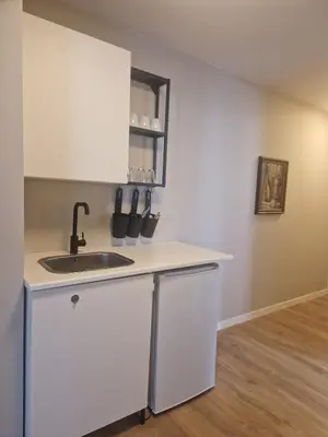 a kitchen with white cabinets and a sink at Cozy Retreat in the Heart of Ålesund in Ålesund