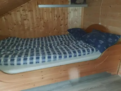 a bed in a wooden cabin with blue pillows at Havgløtt in Oksvoll