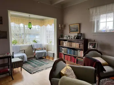 a living room with chairs and a book shelf at Sjarmerende hus med veldig stort uteareal. in Brekstad