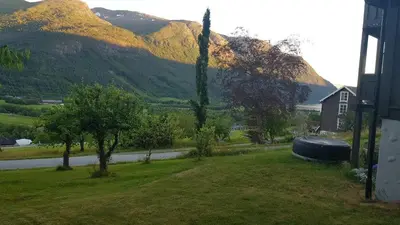 a yard with a house and a road and mountains at Hatlen View in Isfjorden