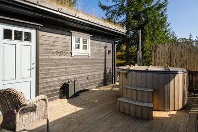 a wooden deck with a hot tub next to a building at Budor - Løvsangeren 7 - 60 min OSL - Badstu - Badestamp - 7 Soverom3 bad in Nordset
