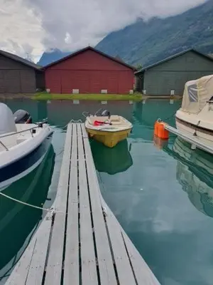 two boats are docked at a dock in the water at Sjarmerende feriehus i Olden rett ved fjorden in Stryn