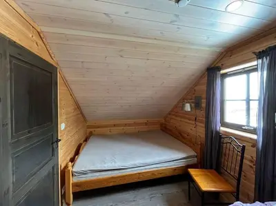 a small bed in a wooden room with a window at Cabin in beautiful surroundings at Harpefossen in Nordfjordeid