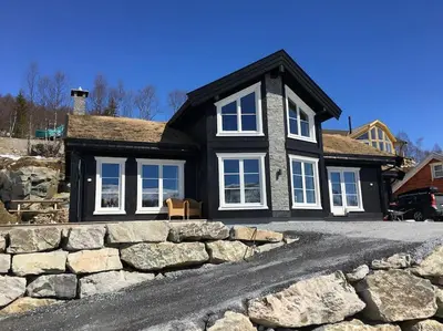 a black house with a stone wall in front of it at Holiday cottage with 4 bedroom on 145m² in Sogndal in Sogndal