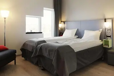 a bedroom with a large bed with white sheets and a window at Scandic Lerkendal in Trondheim
