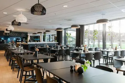 a restaurant with tables and chairs and windows at Scandic Lerkendal in Trondheim